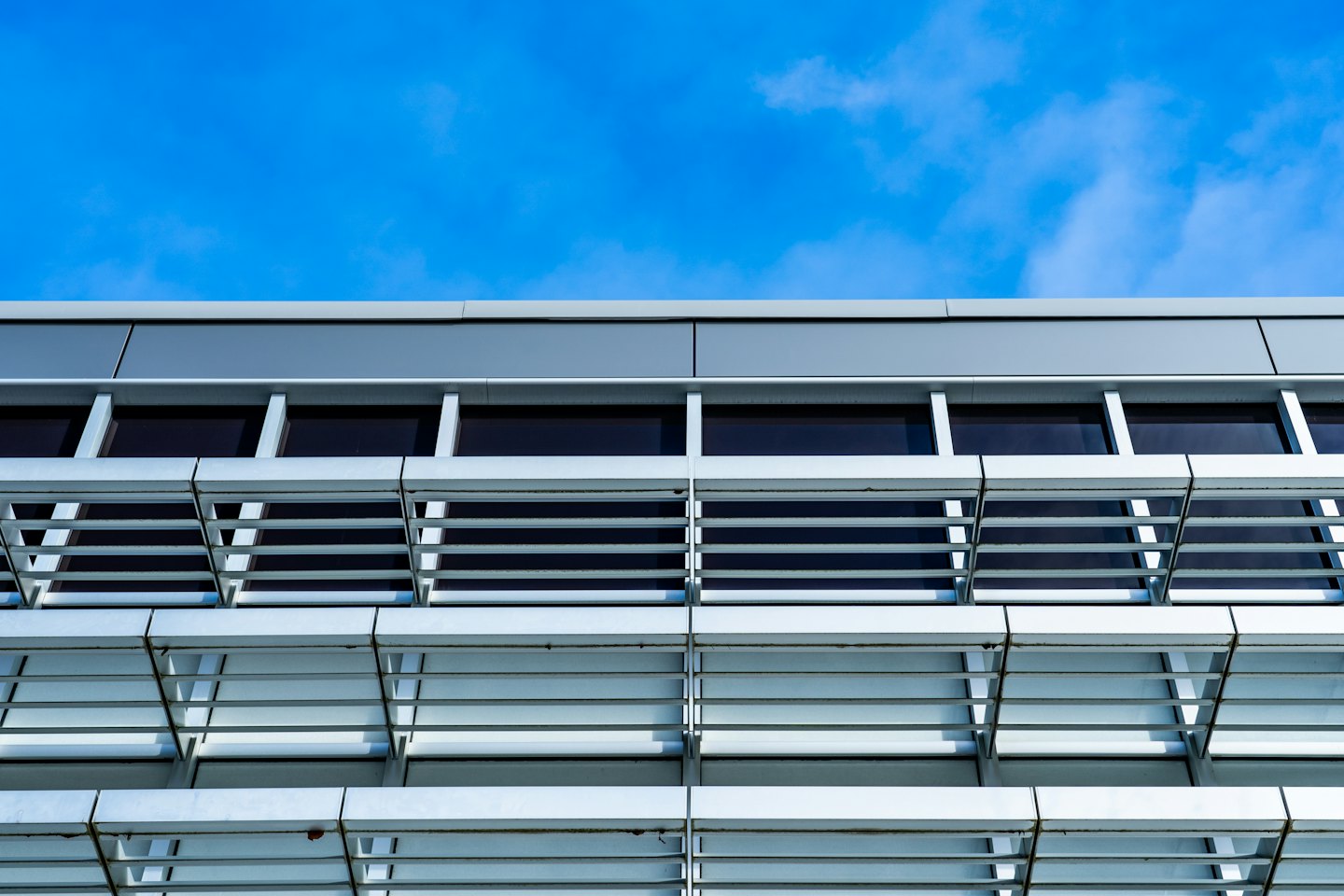 Moderne gebouwgevel met geometrische panelen en verzonken ramen.