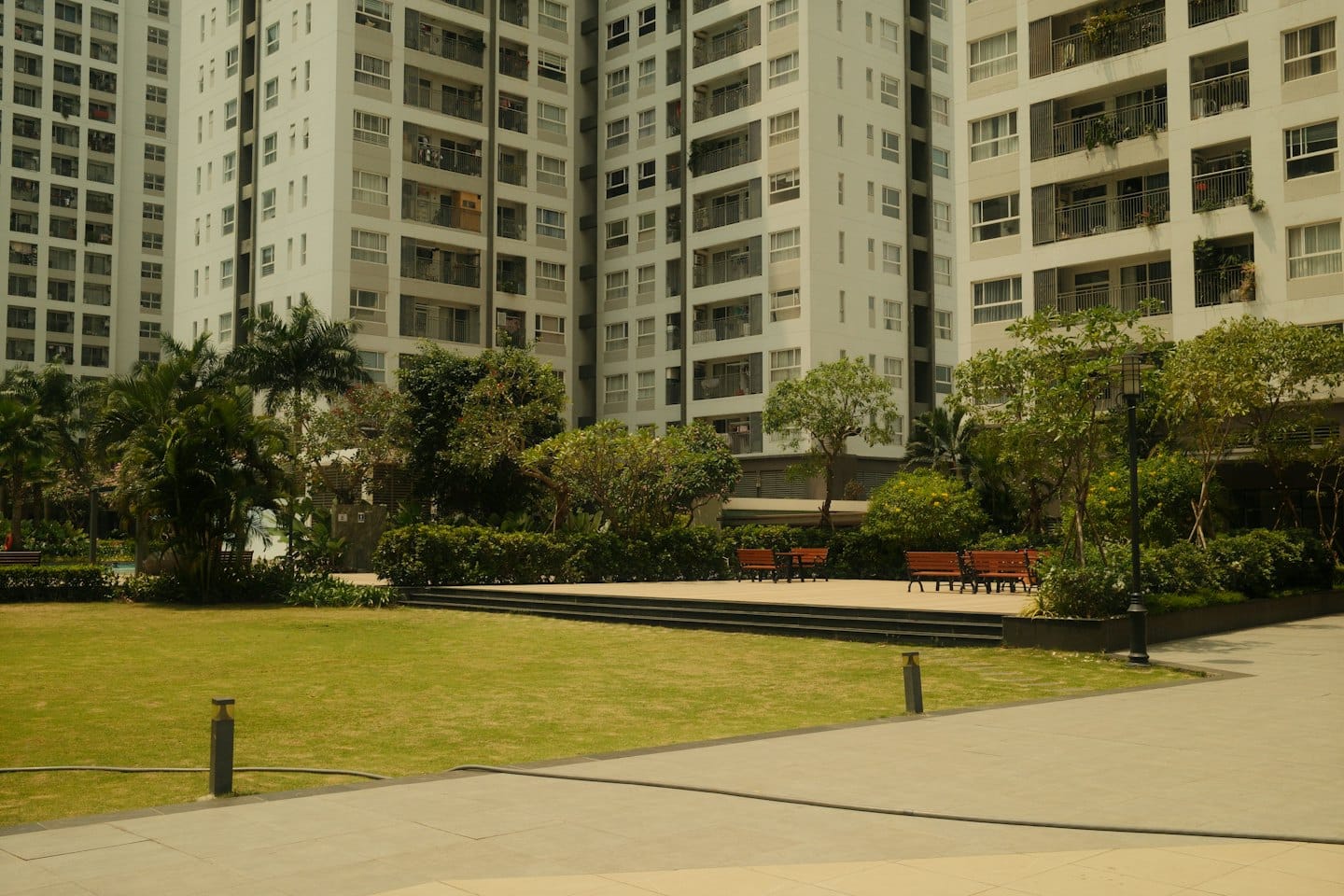 Modern appartementencomplex met een groen gazon en parkbankjes.