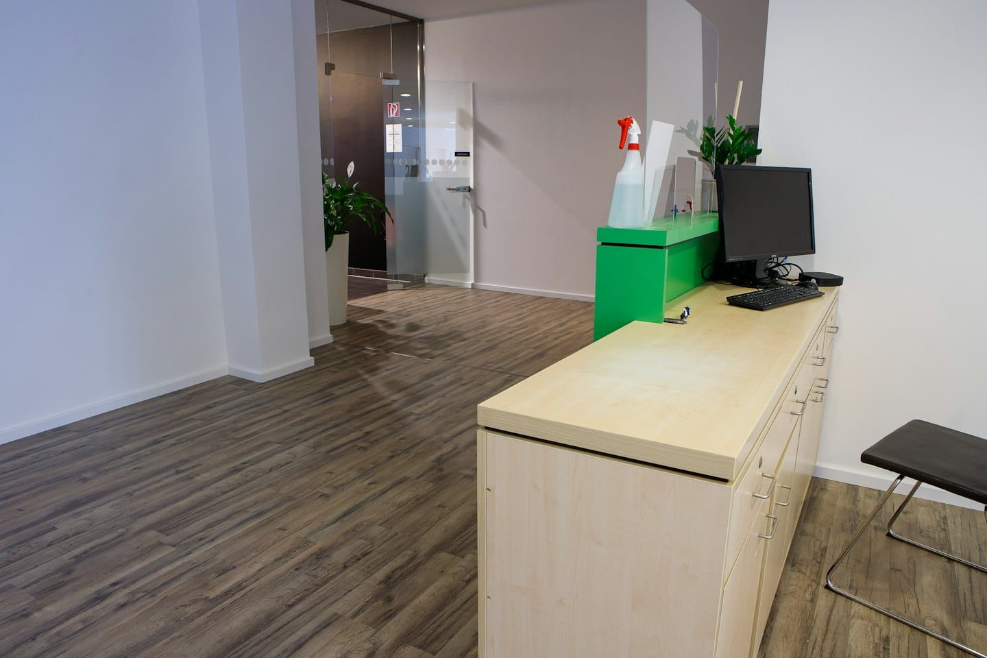 Moderne kantoorontvangstruimte met een houten bureau en planten.