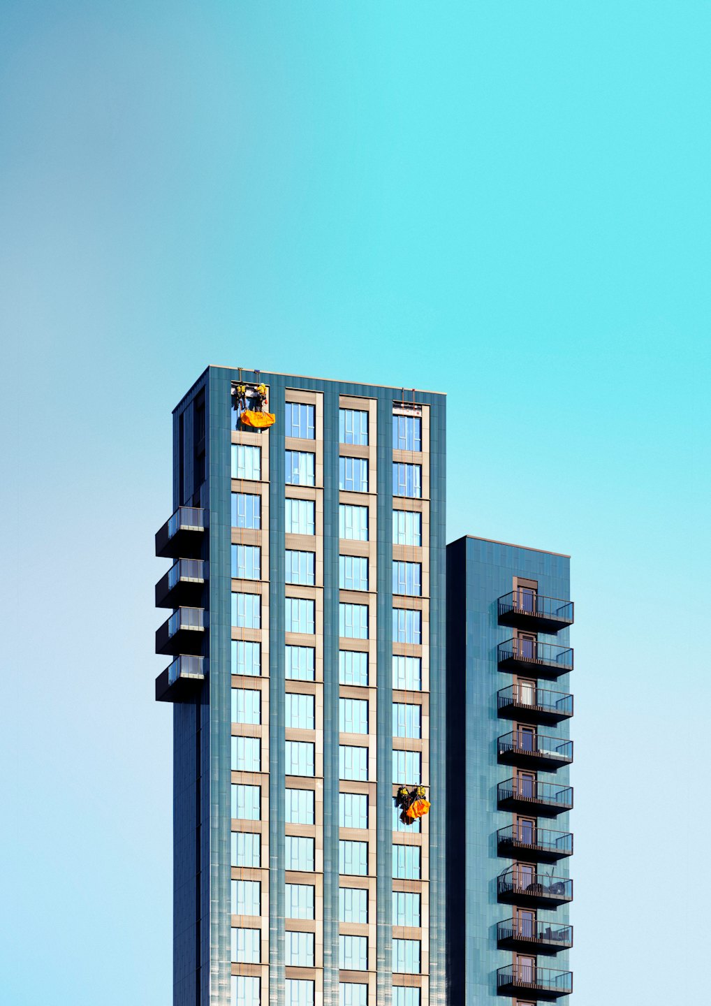 Twee werknemers maken ramen schoon van hoge moderne appartementengebouwen.